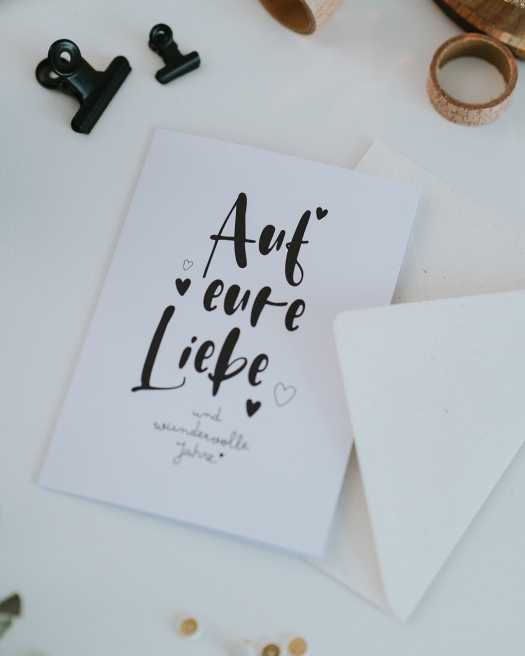 Klappkarte „Auf eure Liebe“ mit geöffnetem Umschlag – Glückwunschkarte zur Hochzeit oder zum Jahrestag.