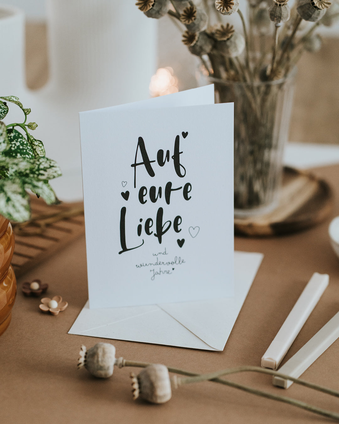 Aufgestellte Hochzeitskarte „Auf eure Liebe und wundervolle Jahre“ mit Umschlag, warmes Handlettering.