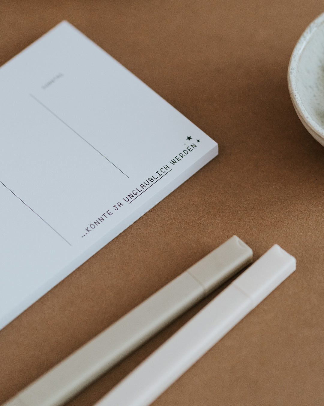 Detail des Wochenplaners mit Schriftzug „…könnte ja unglaublich werden“ auf dickem Papierblock