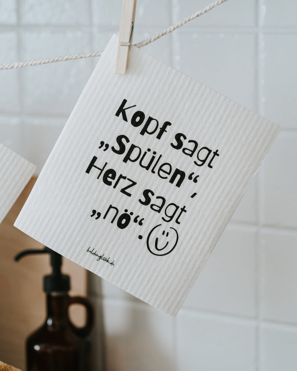 Schwammtuch „Kopf sagt ‚Spülen‘, Herz sagt ‚nö‘.“ hängend.