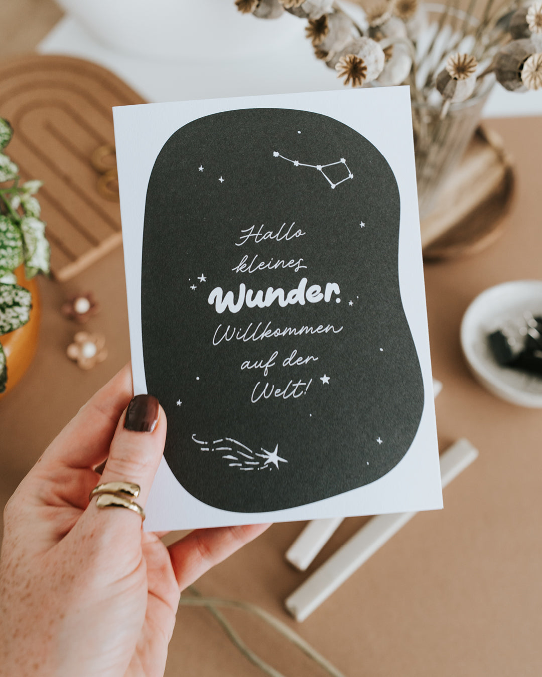 Hand hält Klappkarte „Hallo kleines Wunder. Willkommen auf der Welt!“ auf hochwertigem Papier.