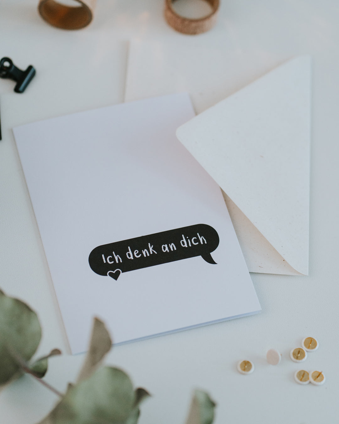 Klappkarte „Ich denk an dich“ auf geöffnetem Umschlag, schwarze Sprechblase mit Herz.