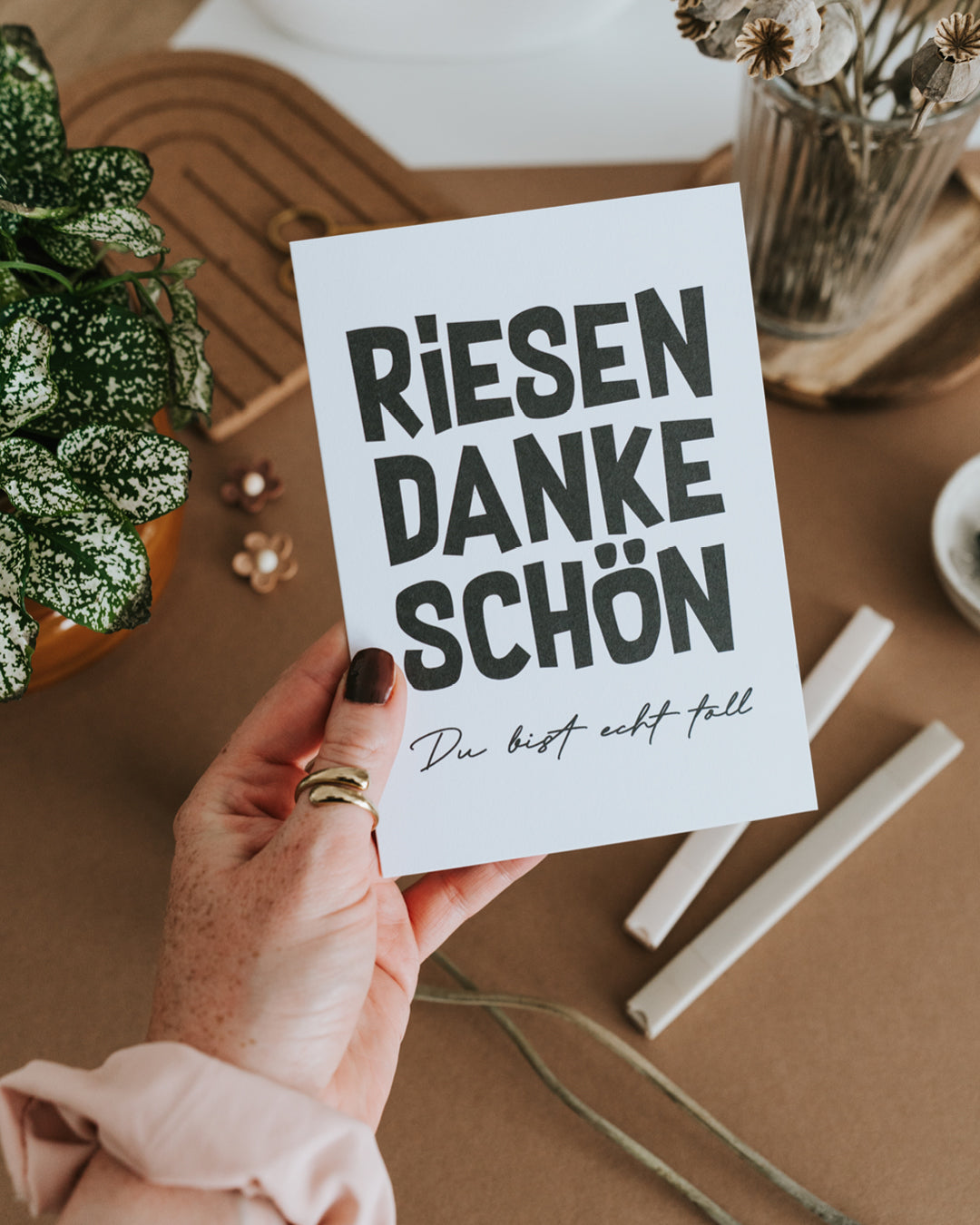 Hand hält Klappkarte „Riesen Dankeschön“ auf hochwertigem Papier im Hochformat.