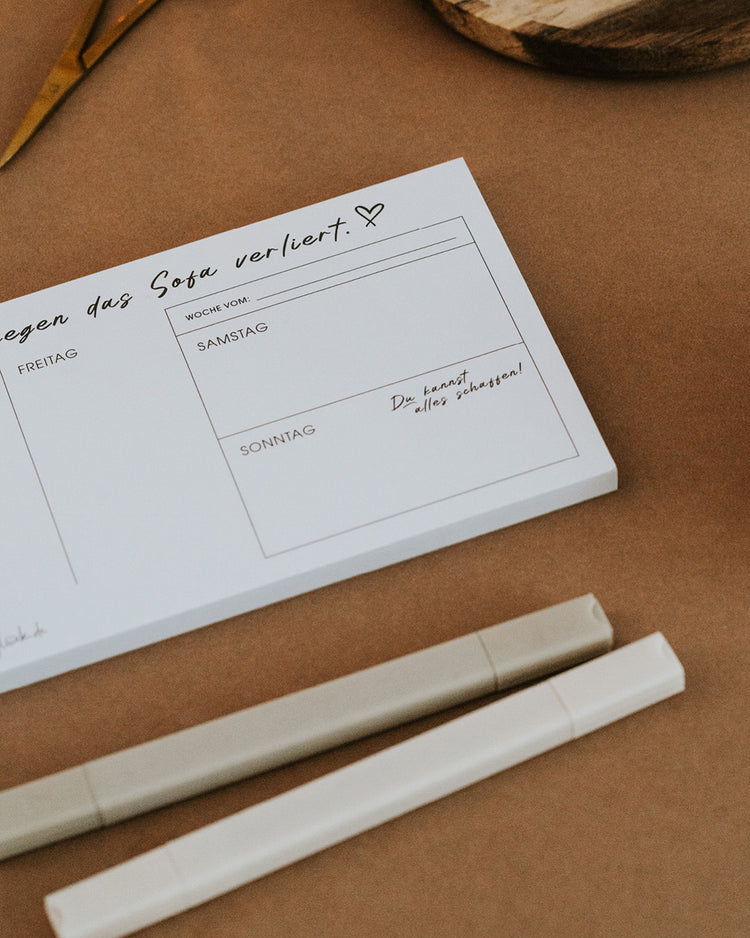 Detail des Wochenplaners mit extra Wochenendfeld und Schriftzug „Zuhause ist da, wo die To-do-Liste gegen das Sofa verliert“