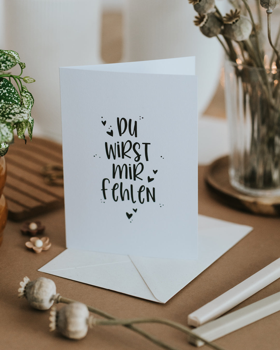 Abschiedskarte „Du wirst mir fehlen“ aufgestellt vor Umschlag, zeitloses Schwarz-Weiß-Lettering.