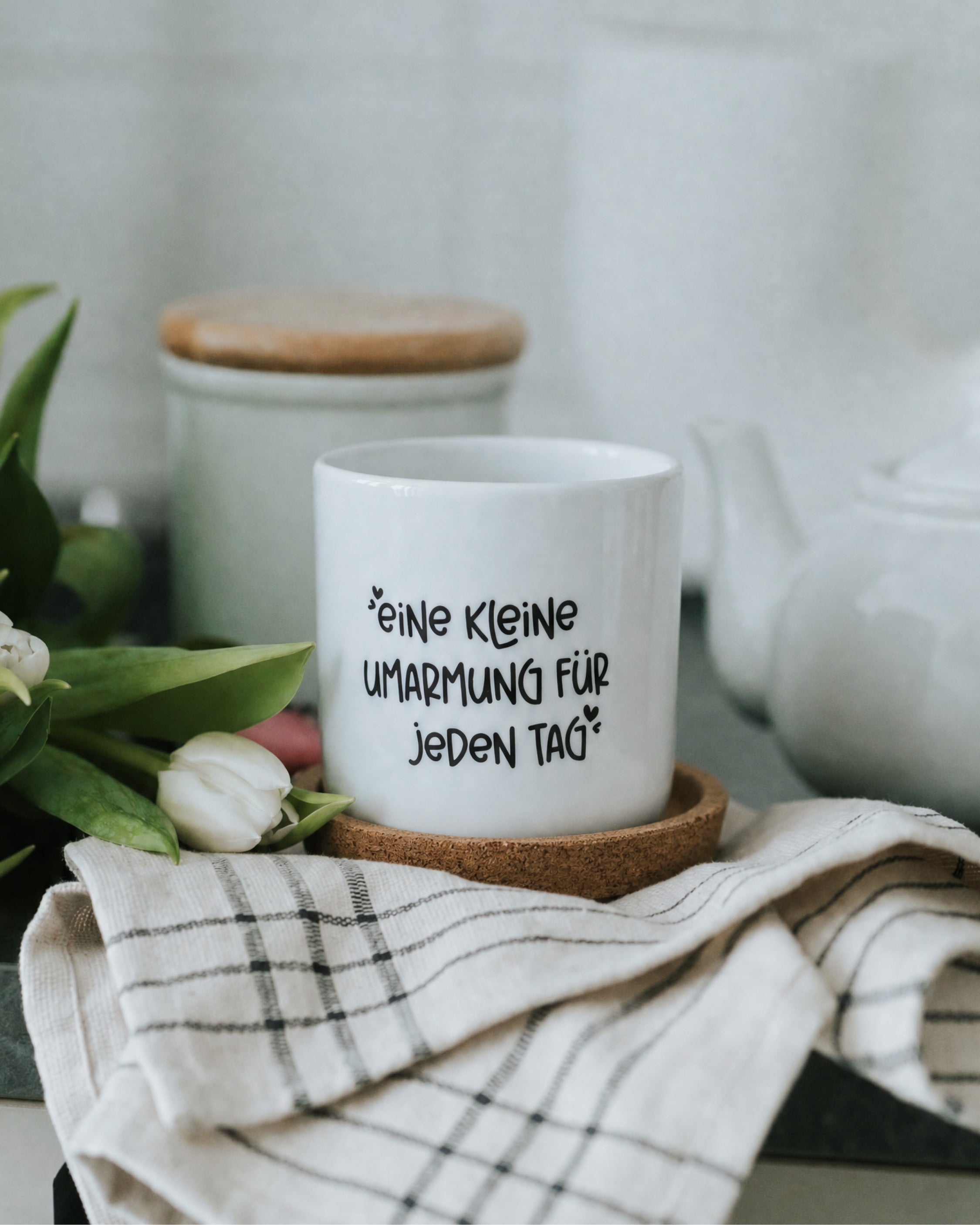 Weißer Becher aus Porzellan mit schwarzem Schriftzug
